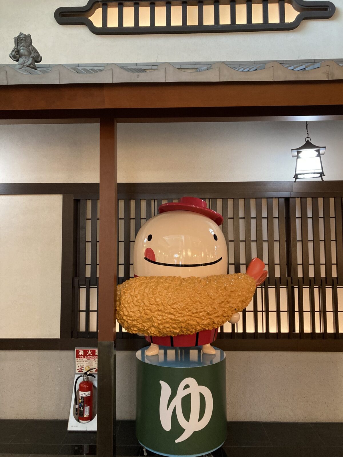セントレアのオリジナルキャラクターの「なぞの旅人フー」が「ゆ」の上にエビフライを持って立っているというインパクトのある像